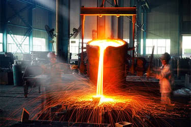 Worker pouring molten steel in an industrial foundry